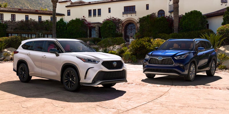 A white and a blue Toyota Highlander parked outside a Mediterranean-style villa